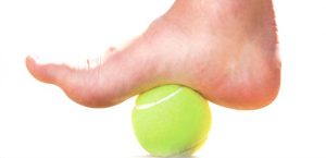 pie sobre una pelota de tenis. Uno de los ejercicios para curar la fascitis plantar